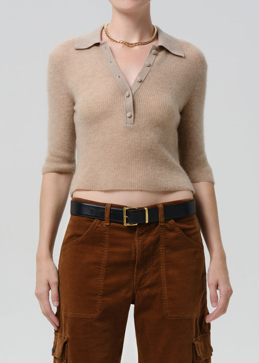 Person wearing a beige ribbed sweater and brown cargo pants on a grey background