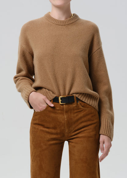 Person wearing a brown sweater and brown pants on a grey background