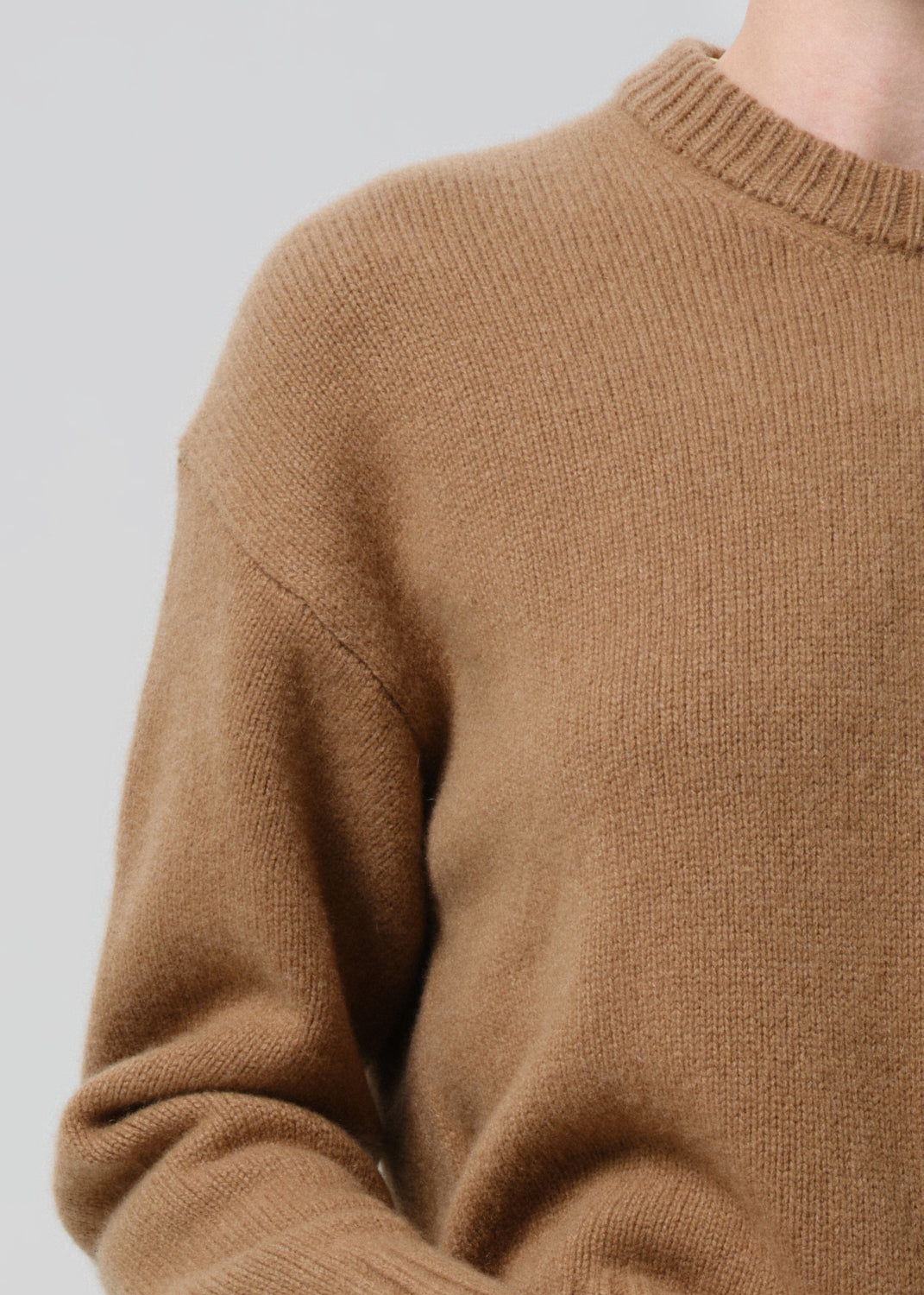 Brown sweater worn by a person on a grey background