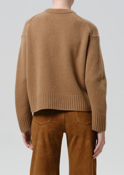Person wearing a brown sweater and pants on a grey background
