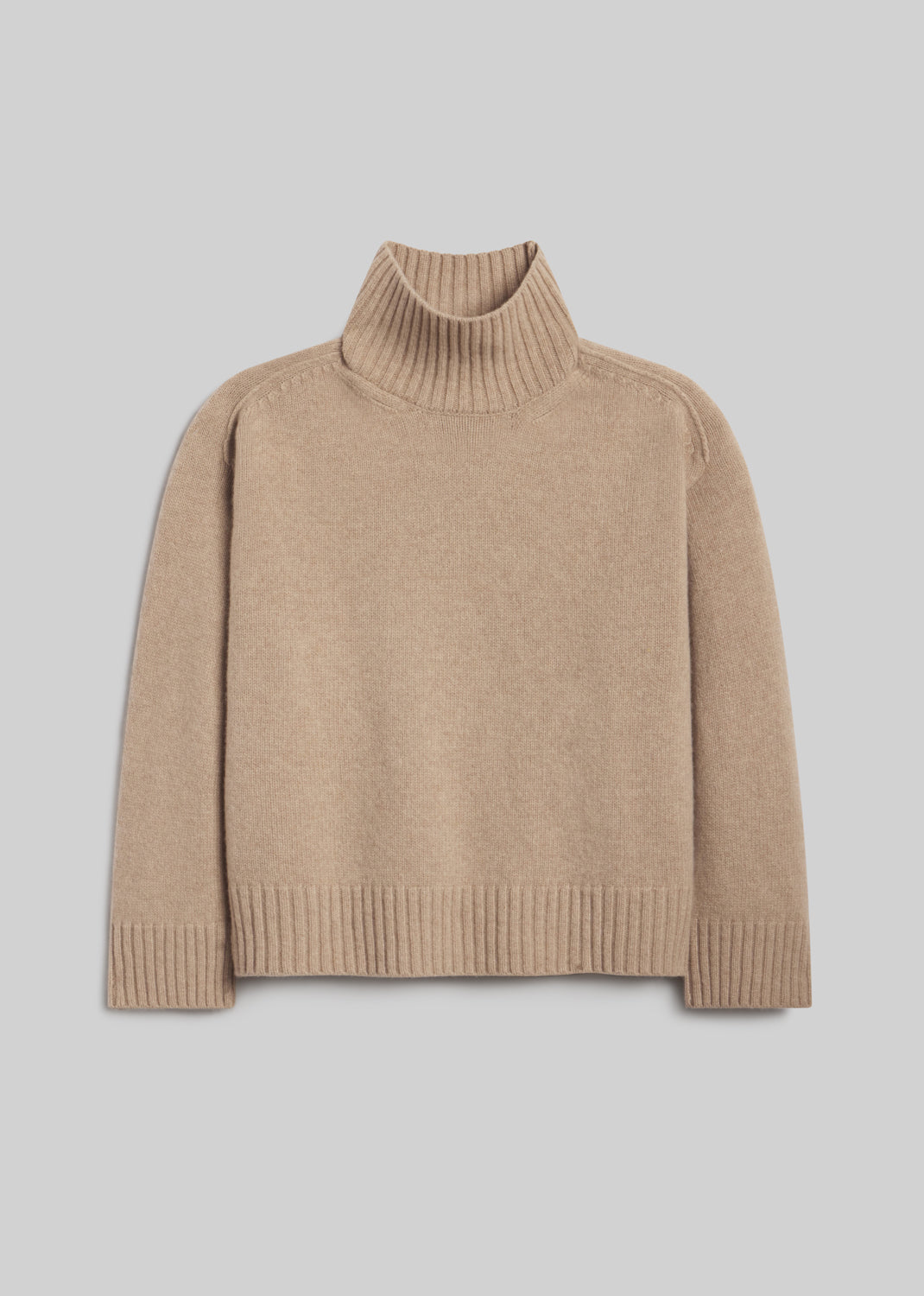 Scout Turtleneck Sweater in Fawn, featuring a relaxed silhouette, light beige knit, ribbed turtleneck, long sleeves, and ribbed cuffs and hem, front view on a grey background.
