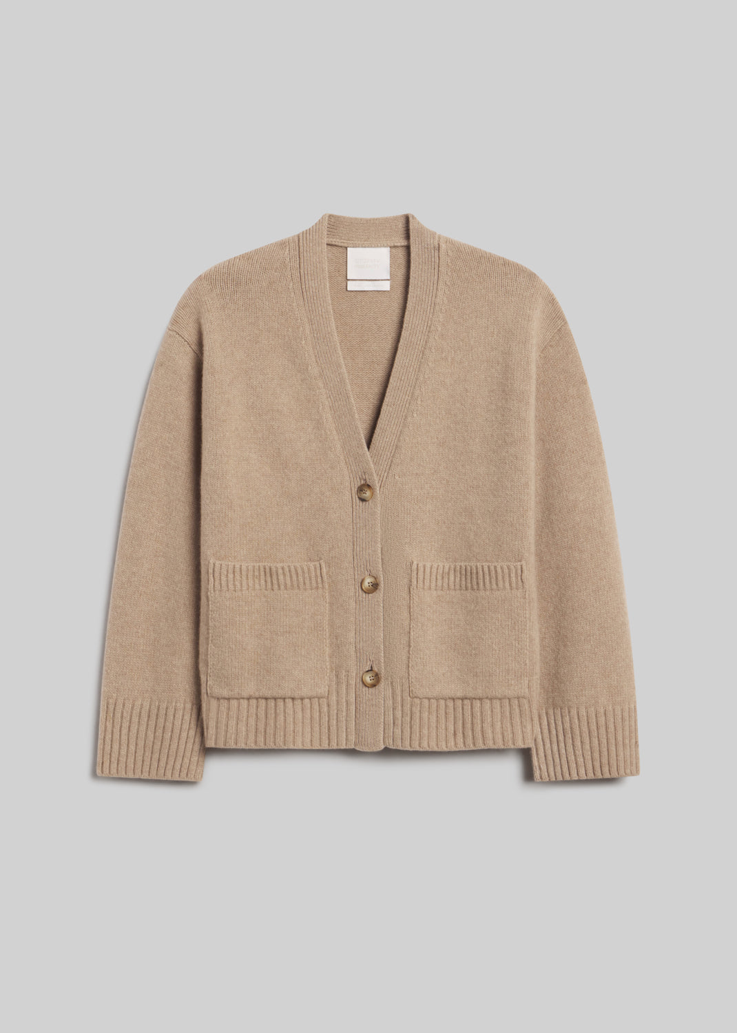 Essential Slouchy Cardigan Sweater in Fawn, featuring a relaxed fit, V-neckline, three-button front closure, two patch pockets, and ribbed cuffs and hem, front view on a grey background.