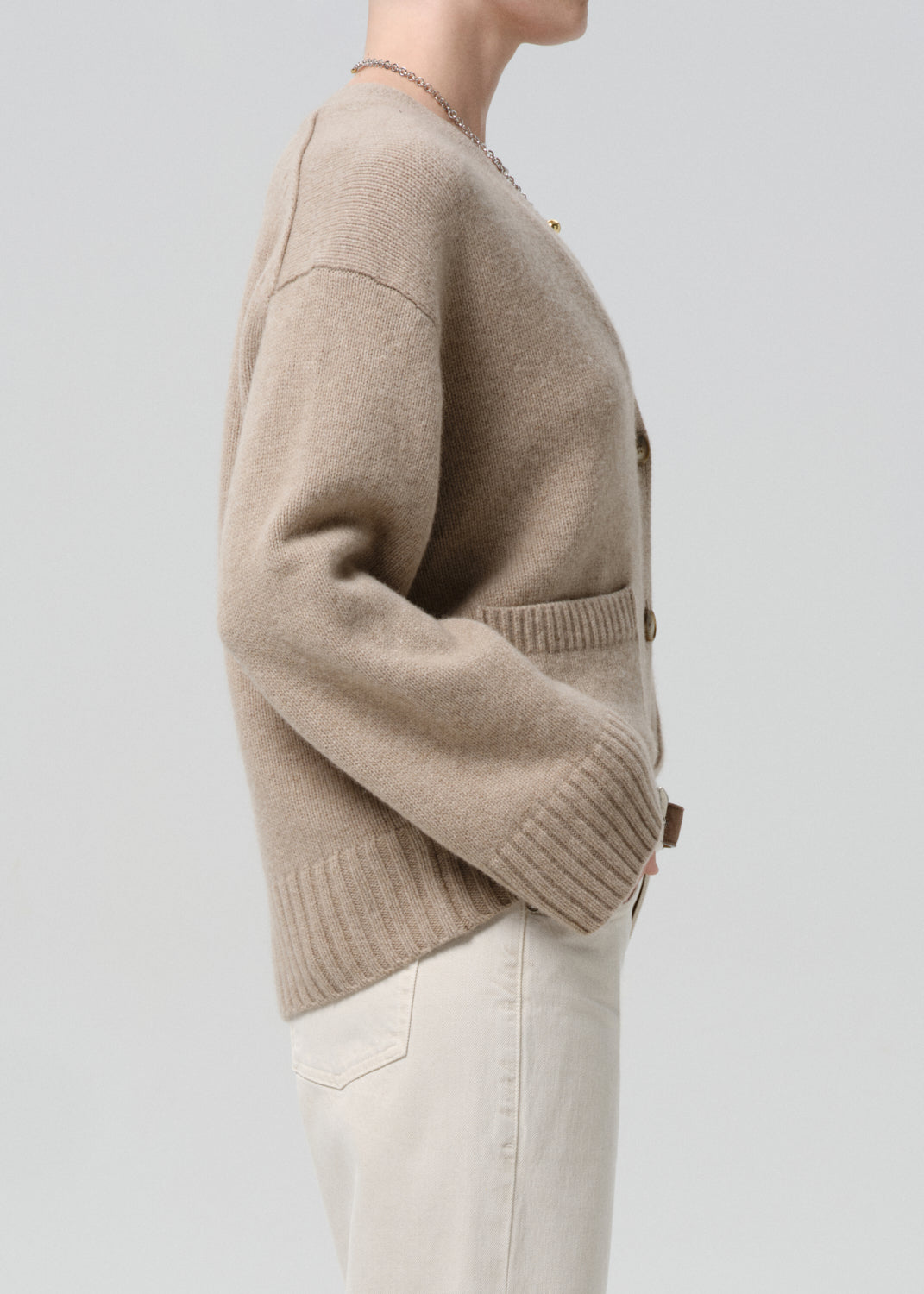 Beige cardigan worn by a person on a grey background