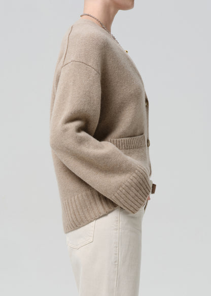 Beige cardigan worn by a person on a grey background