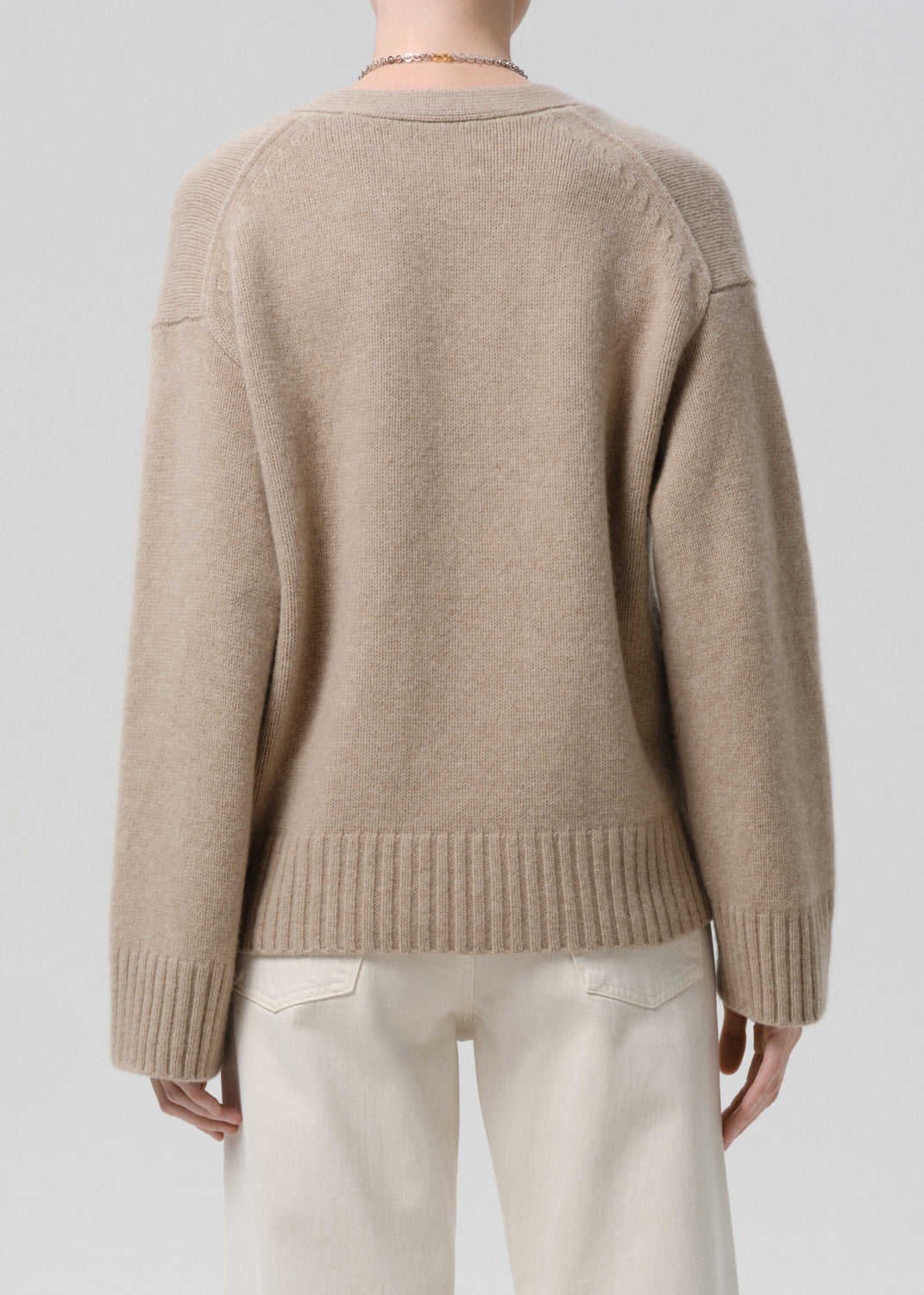 Beige sweater worn by a person on a grey background