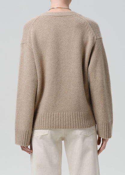 Beige sweater worn by a person on a grey background