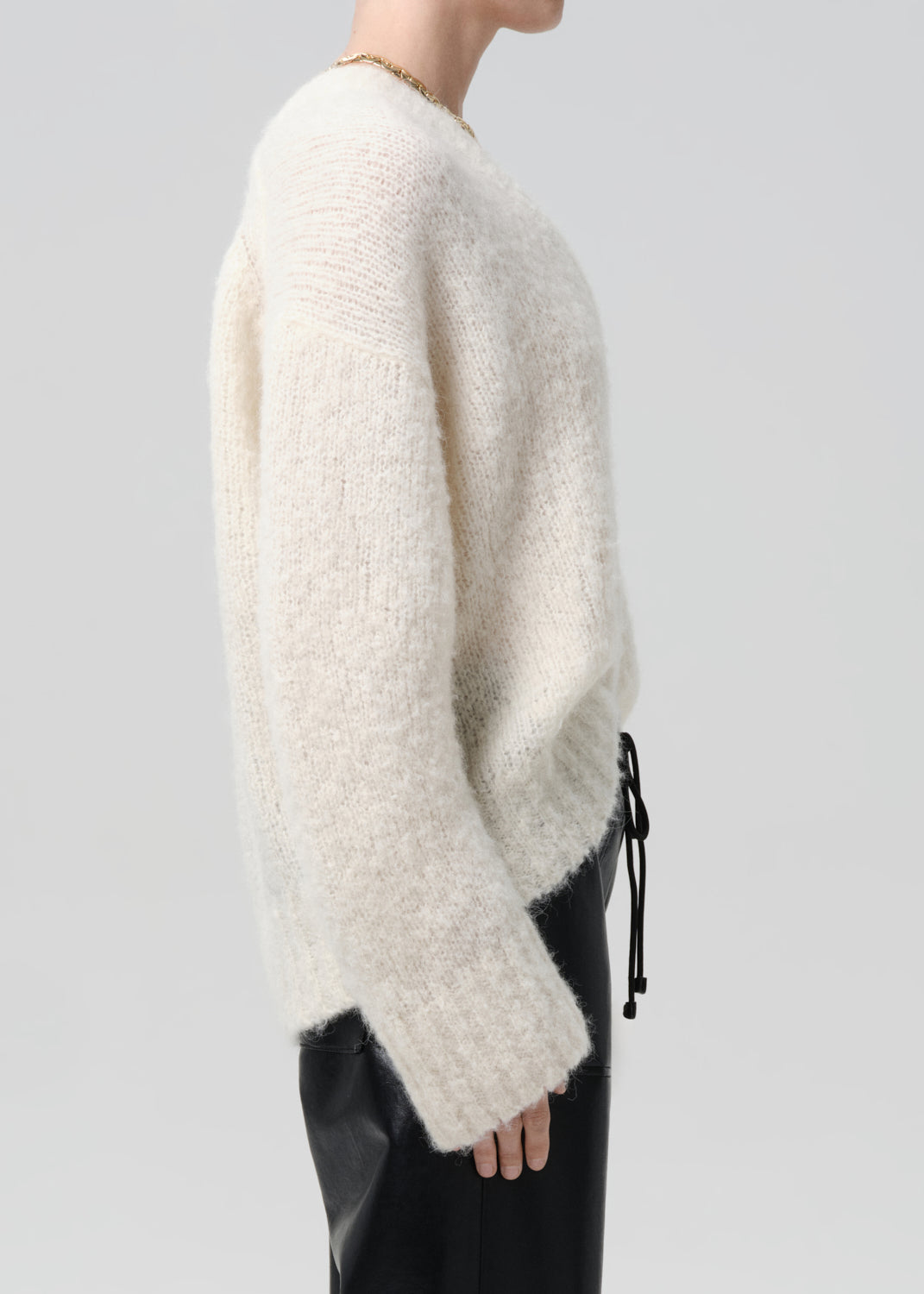 White fuzzy sweater worn by a person on a grey background