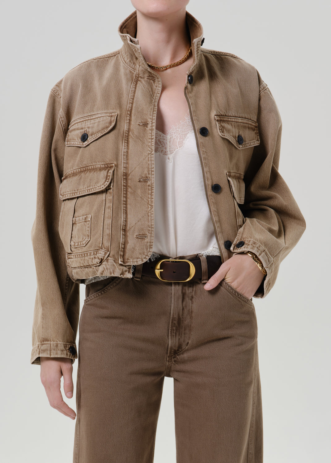 Person wearing tan jacket with pants on a grey background