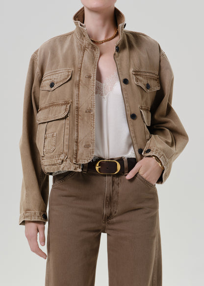 Person wearing tan jacket with pants on a grey background