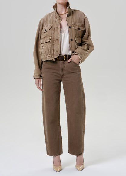Person wearing tan jacket with pants on a grey background