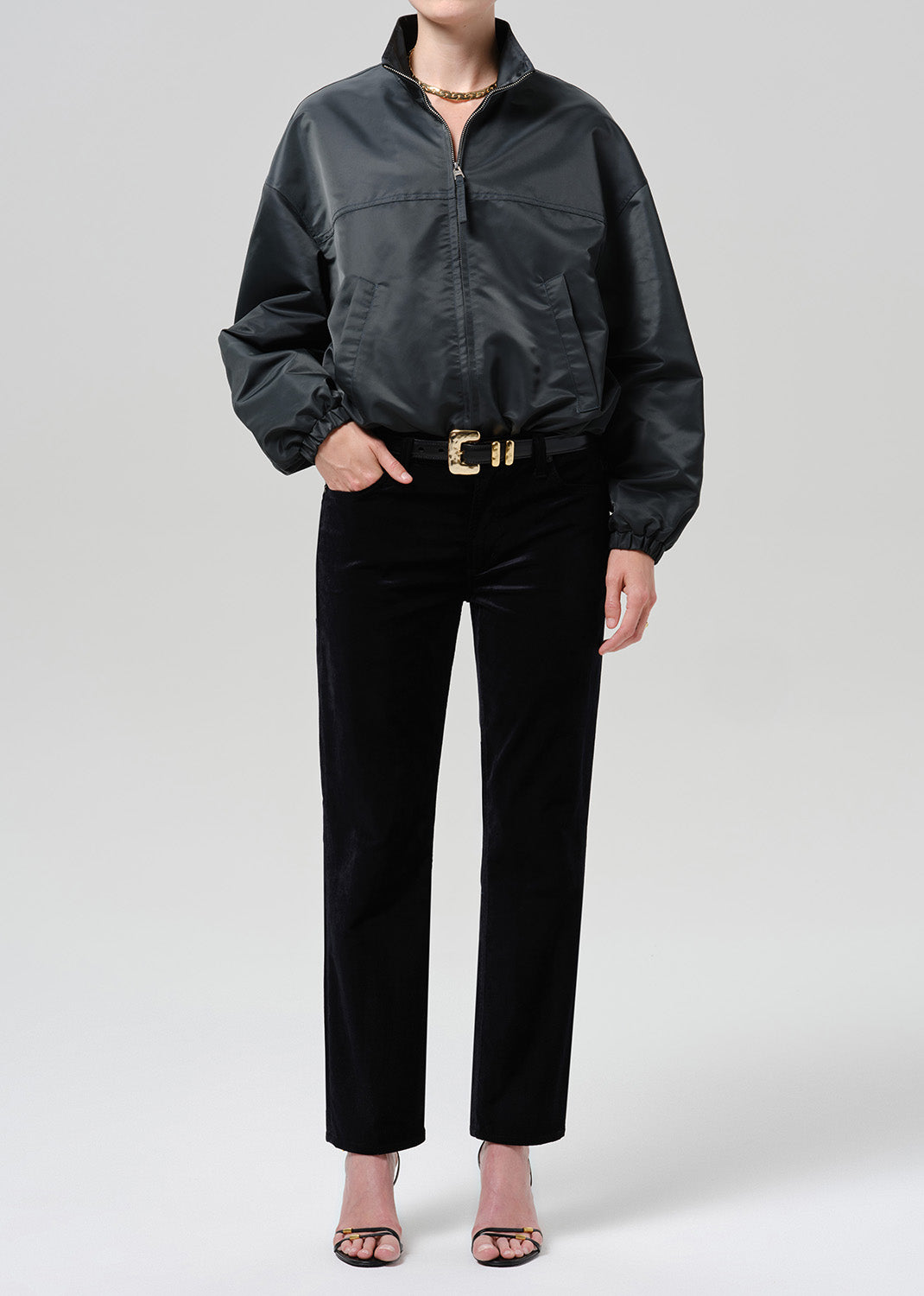 Person wearing dark green nylon jacket paired with black pants