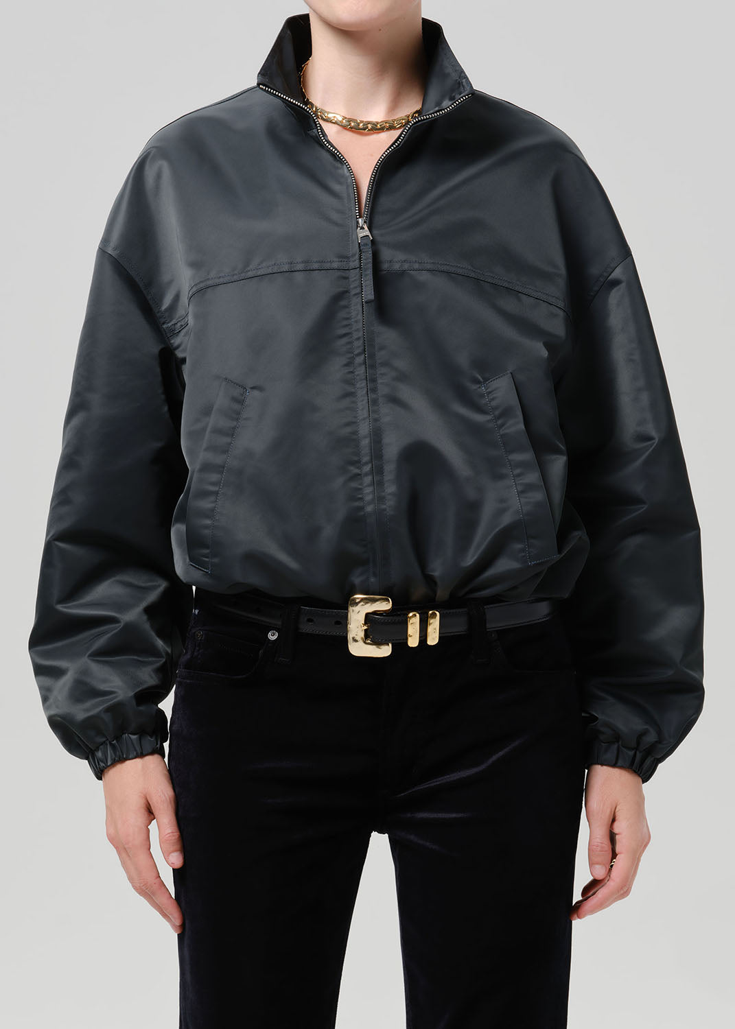 Person wearing dark green nylon jacket paired with black pants