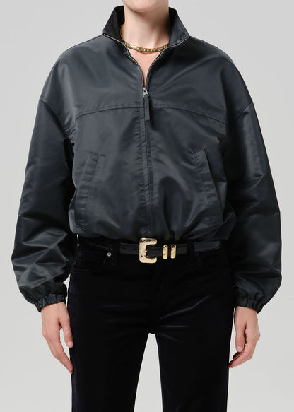 Person wearing dark green nylon jacket paired with black pants