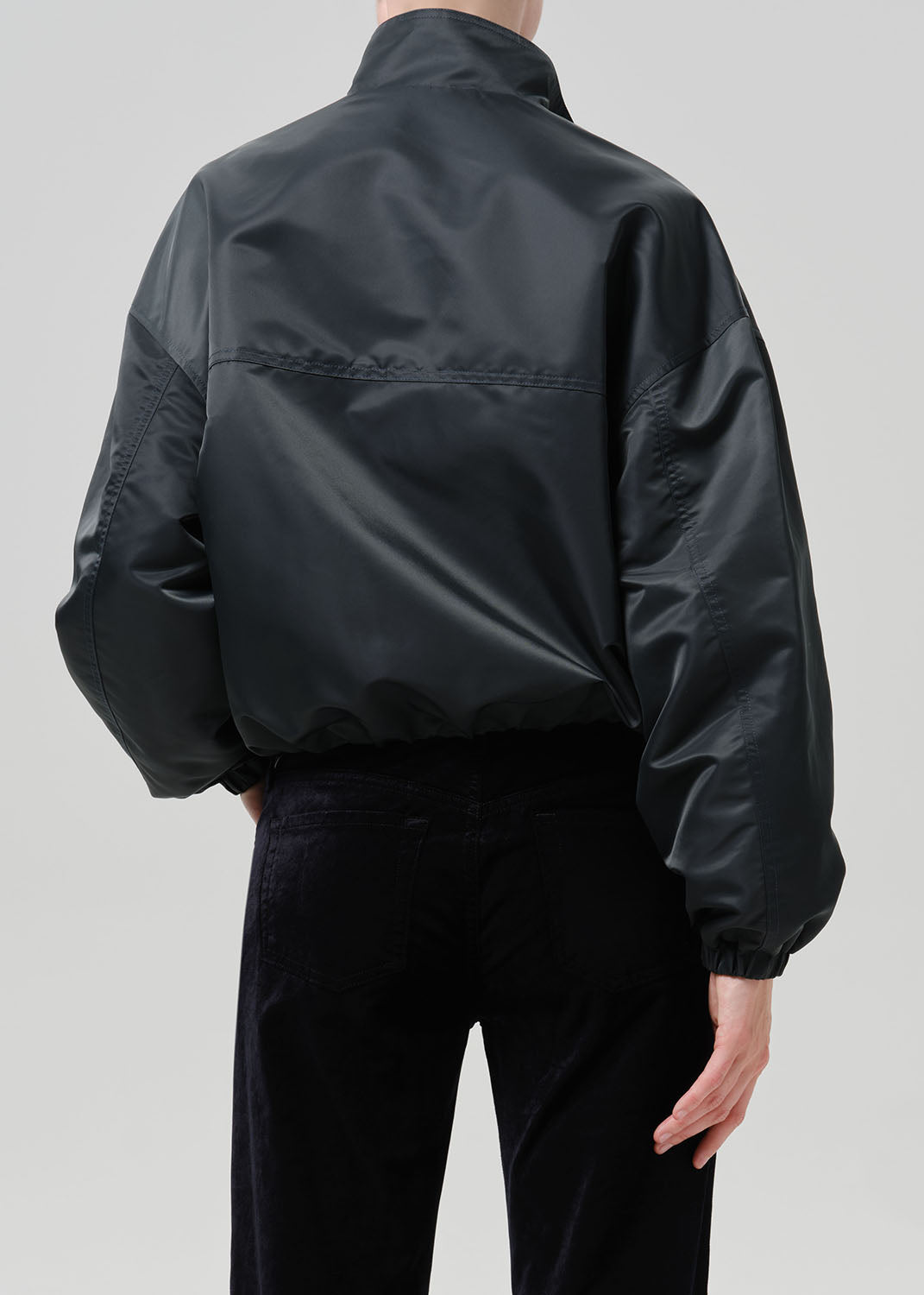 Person wearing dark green nylon jacket paired with black pants