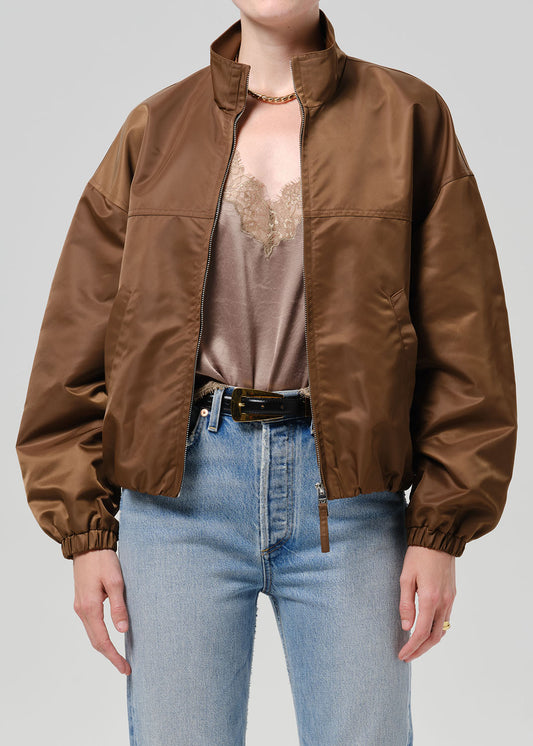 Person wearing a brown nylon jacket paired with blue jeans