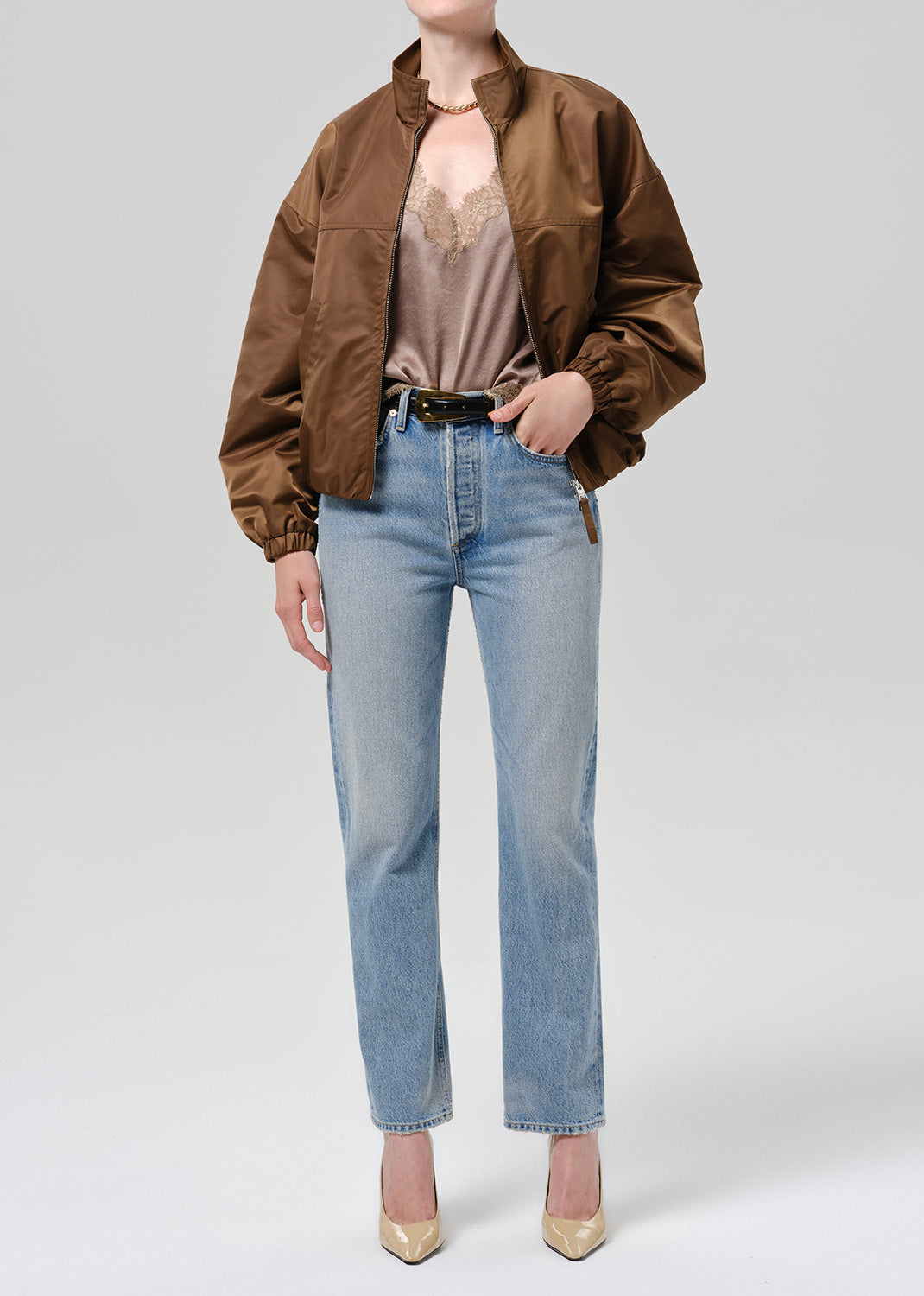 Person wearing a brown nylon jacket paired with blue jeans