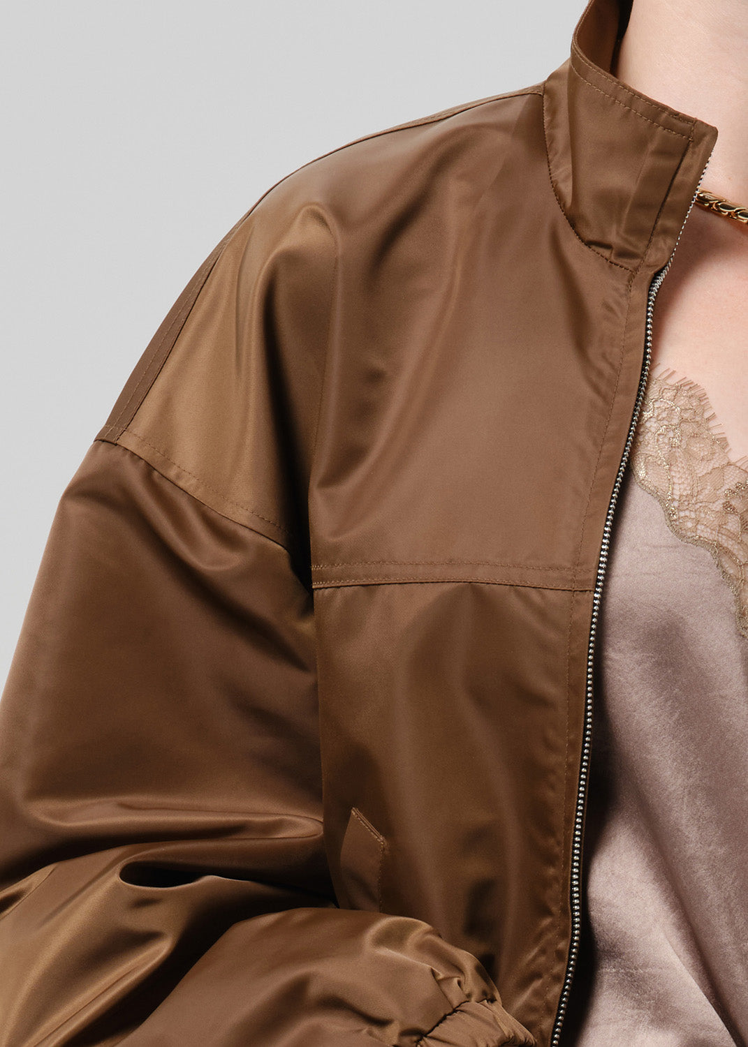 Person wearing a brown nylon jacket paired with blue jeans