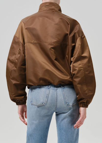 Person wearing a brown nylon jacket paired with blue jeans