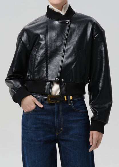 Person wearing a black leather jacket and blue jeans on a grey background