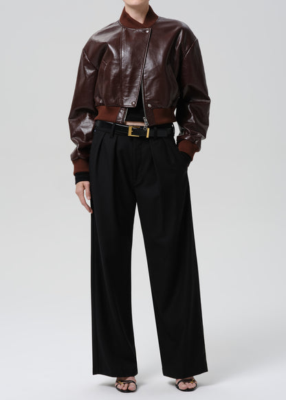 Person wearing a dark red leather jacket and black pants on a grey background