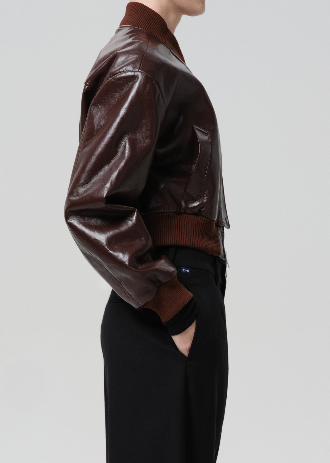 Dark red leather jacket worn by a person on a grey background