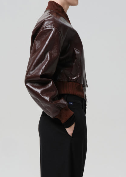 Dark red leather jacket worn by a person on a grey background