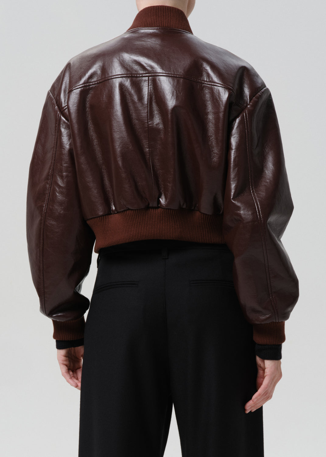 Dark red leather jacket worn by a person on a grey background