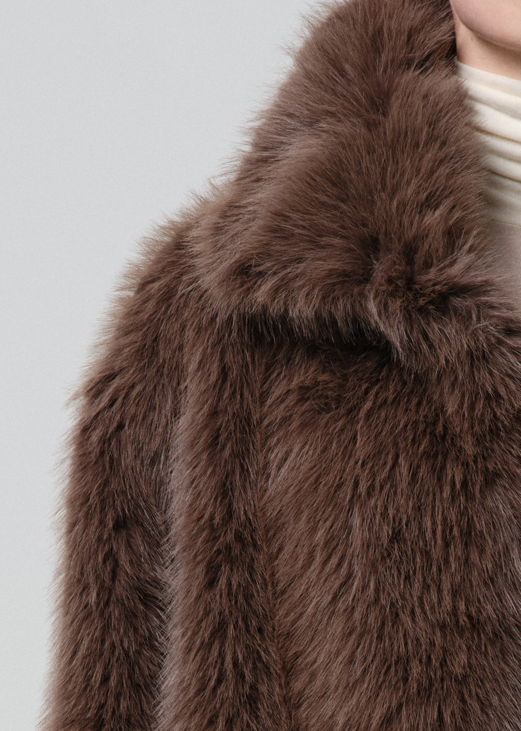 Close-up of a brown faux fur jacket on a grey background