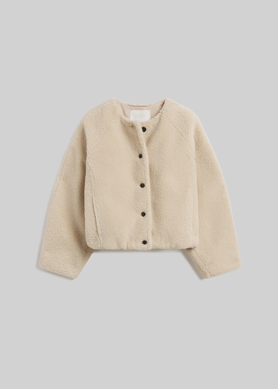 Cream sherpa boucle collarless jacket with button front on grey background