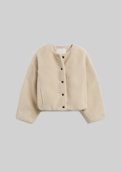 Cream sherpa boucle collarless jacket with button front on grey background