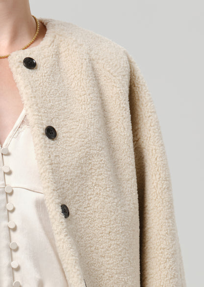 Close-up of a cream boucle jacket on a grey background