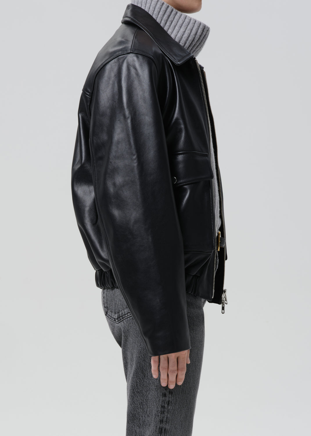 Person wearing a black leather jacket on a grey background