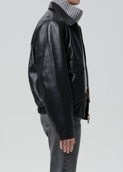 Person wearing a black leather jacket on a grey background
