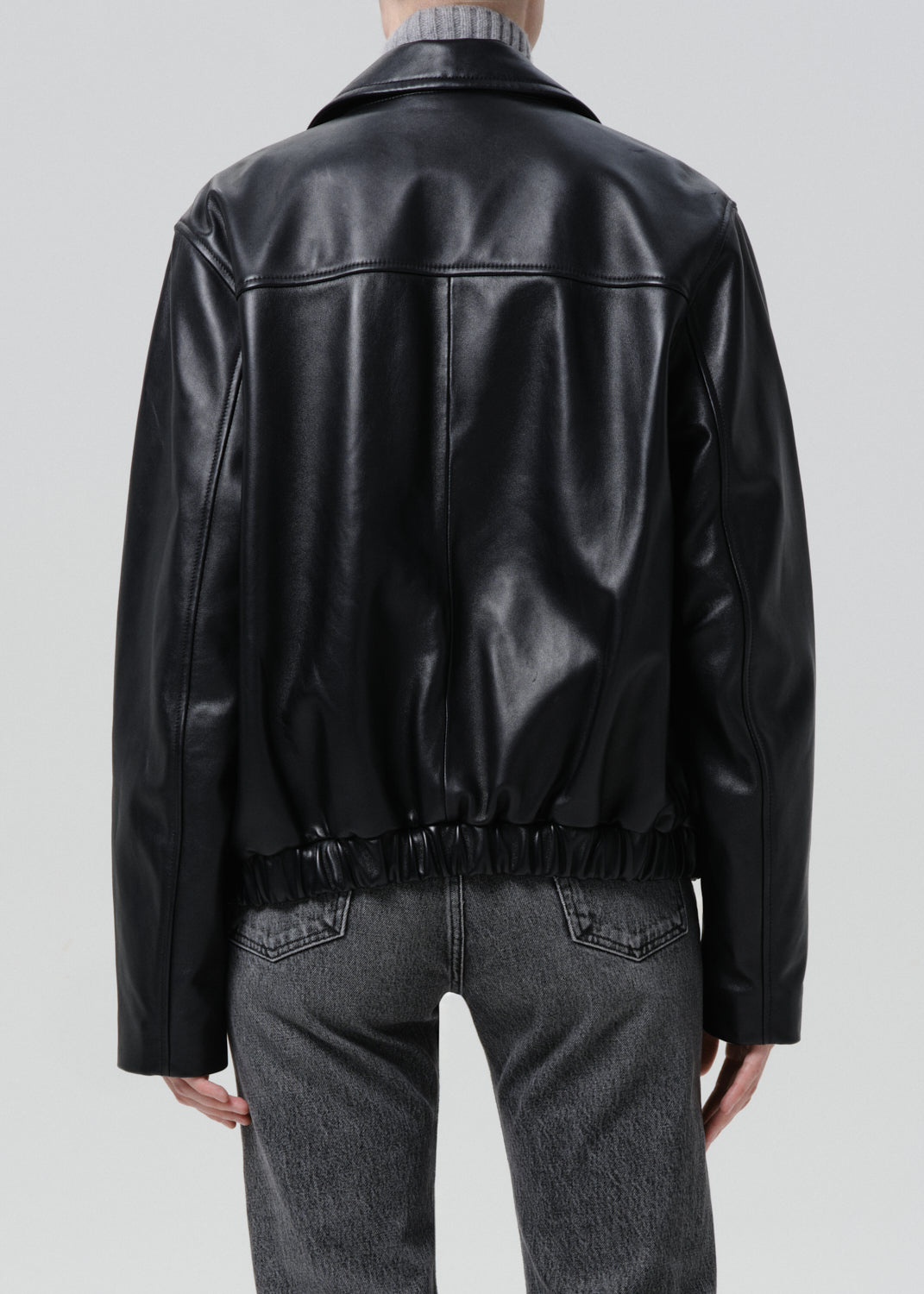 Black leather jacket worn by a person on a grey background