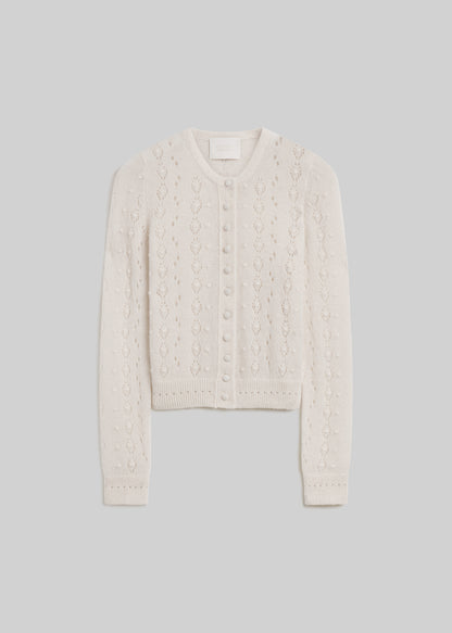 Cream long-sleeve pointelle knit cardigan sweater with a round neckline, covered front buttons, delicate openwork detailing, and ribbed cuffs and hem, front flat lay view on a grey background.