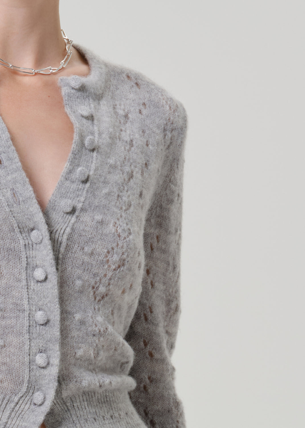 Close-up of a grey button-front cardigan on a grey background.