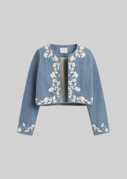 Light blue cropped denim jacket with white floral embroidery on grey background