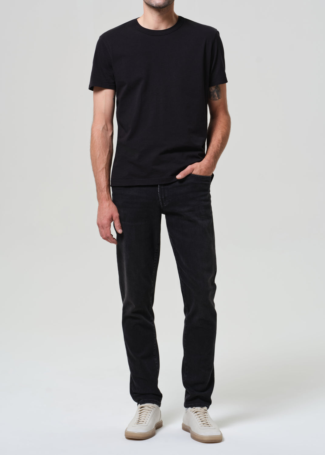 Person wearing black tee with dark washed black jeans