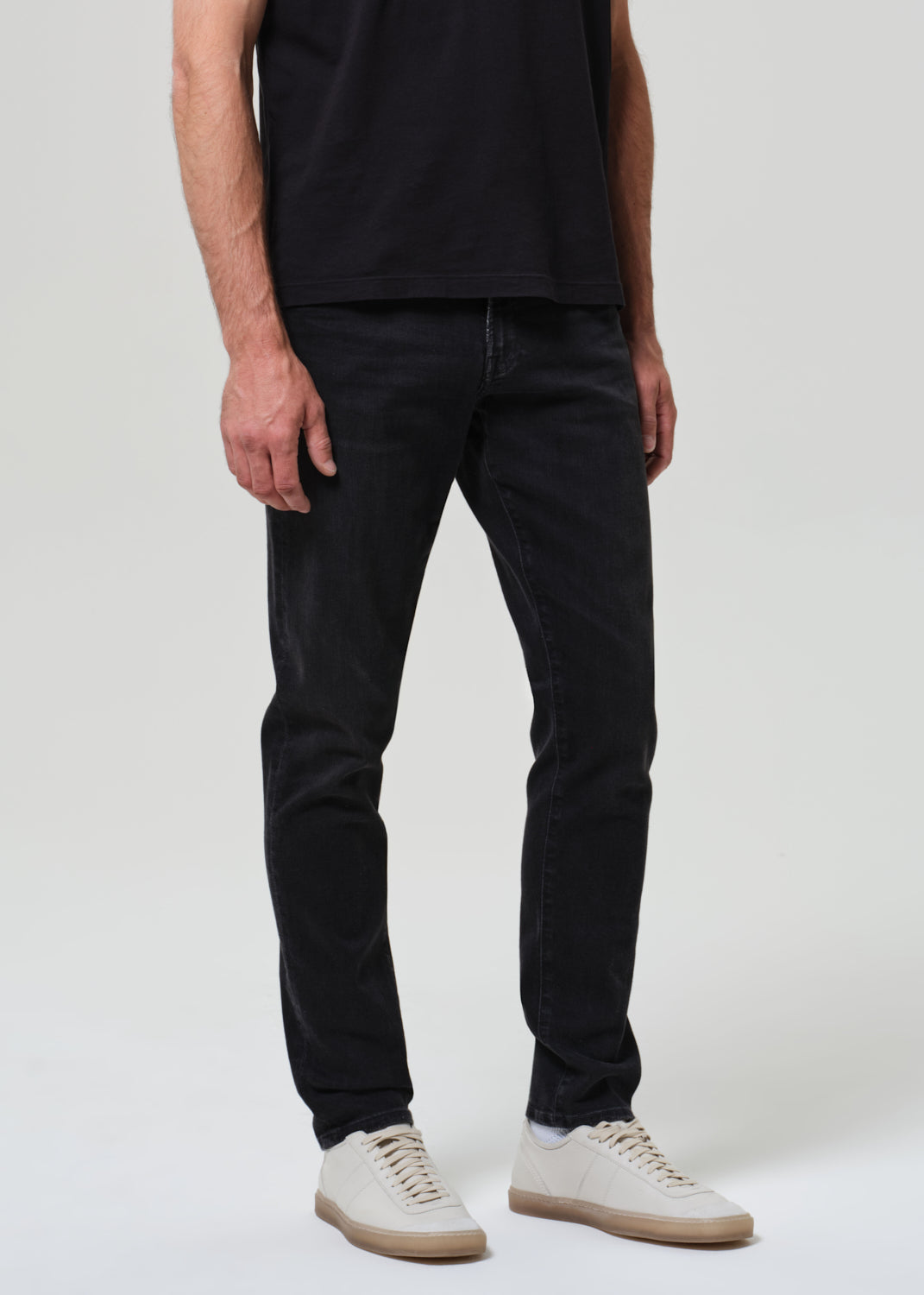 Person wearing black tee with dark washed black jeans