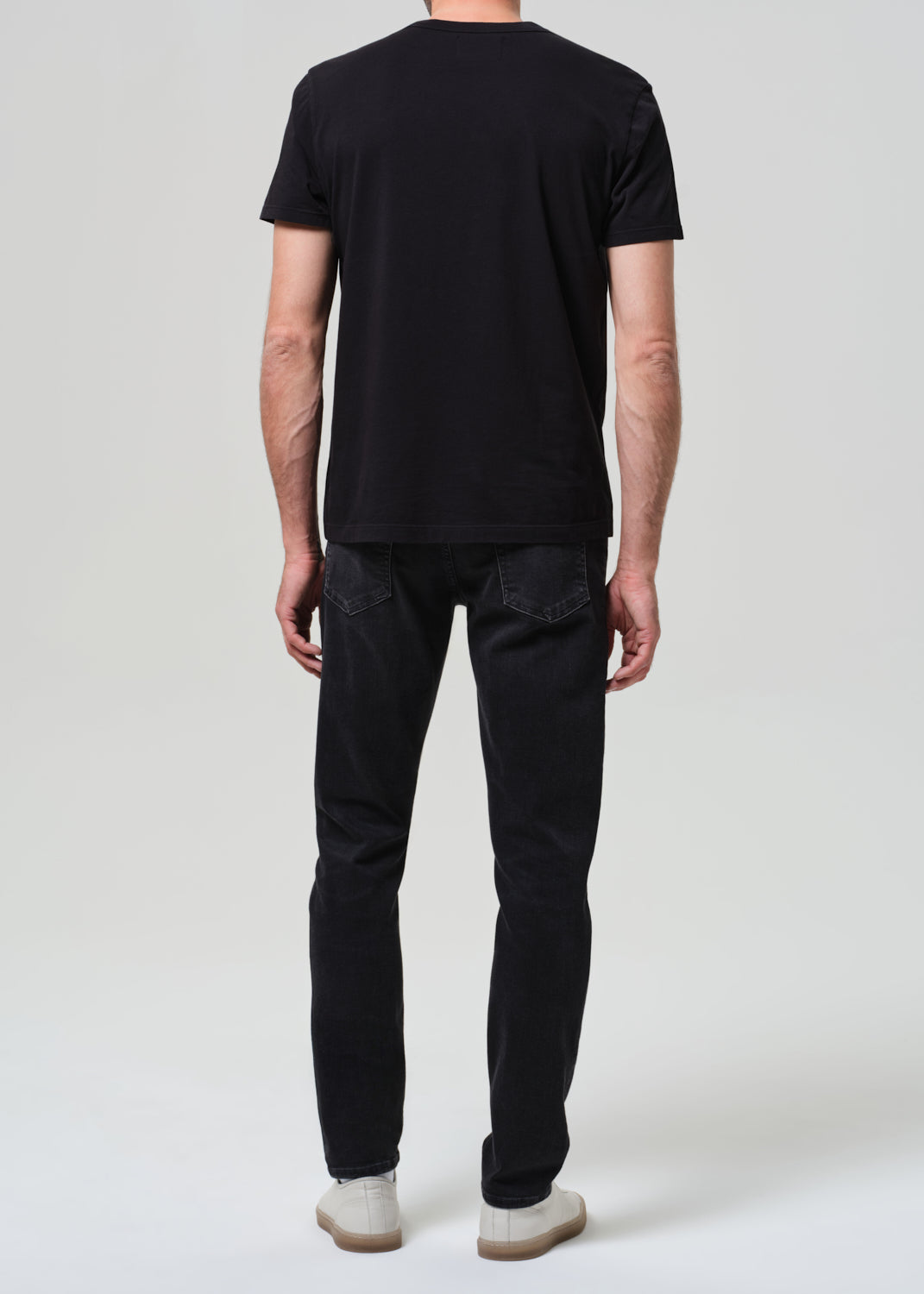 Person wearing black tee with dark washed black jeans