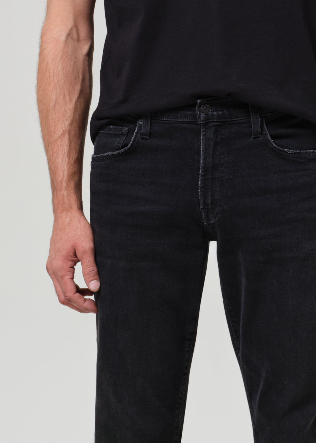 Person wearing black tee with dark washed black jeans