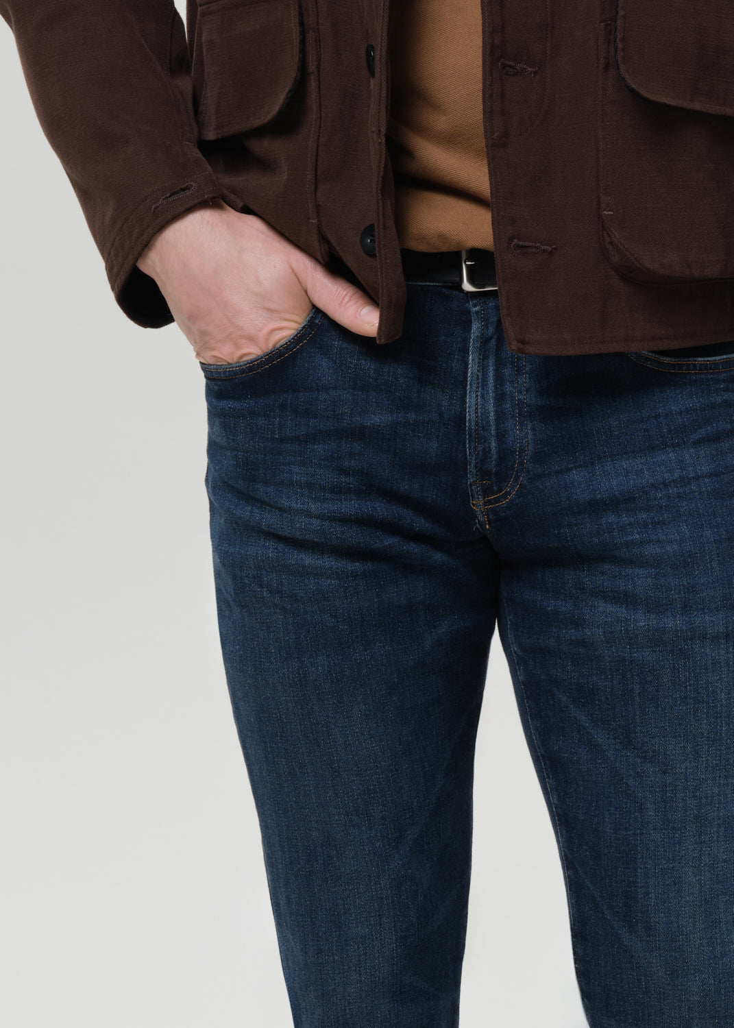 Close-up of dark indigo straight leg jeans on a grey background.