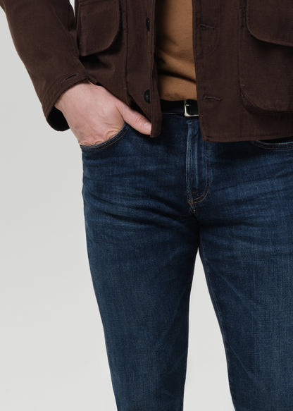 Close-up of dark indigo straight leg jeans on a grey background.