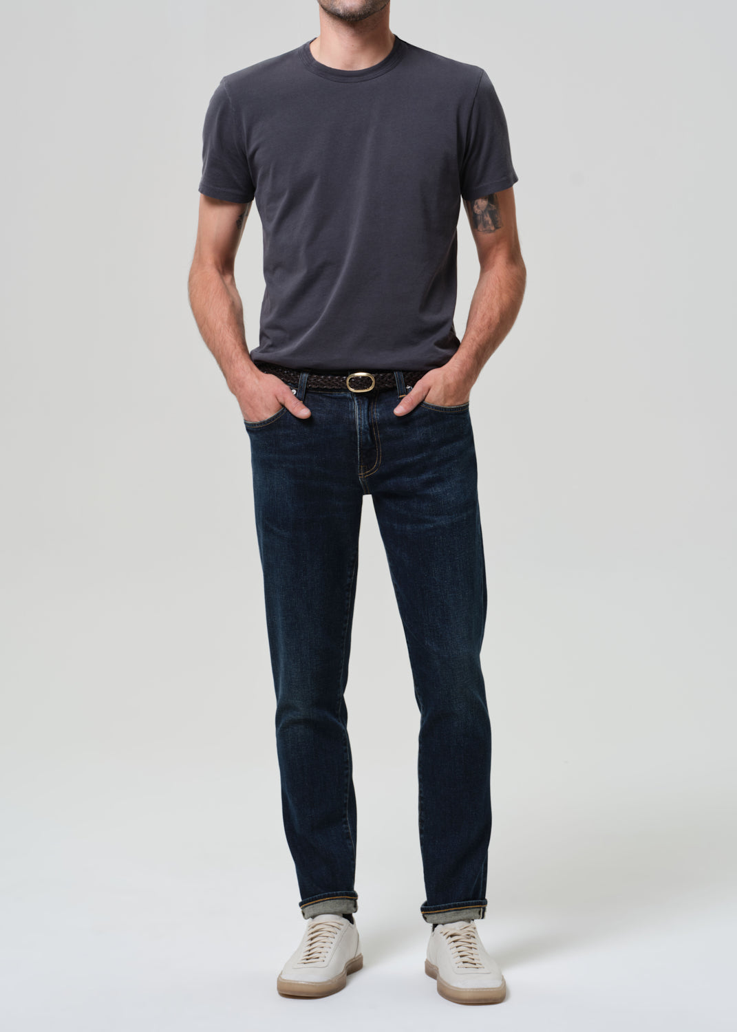 Person wearing grey tee with dark indigo jeans