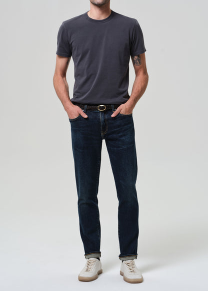 Person wearing grey tee with dark indigo jeans