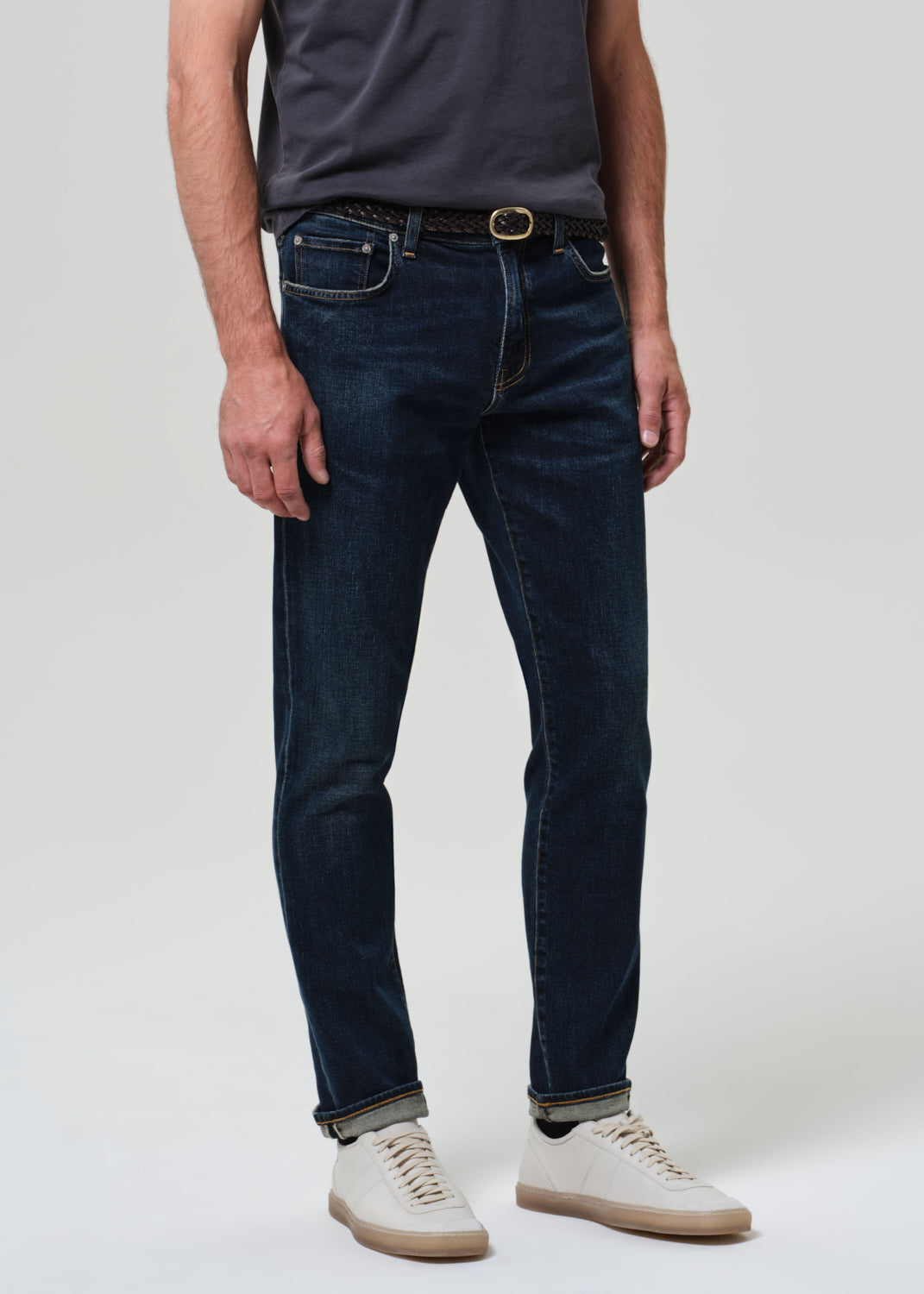 Person wearing grey tee with dark indigo jeans