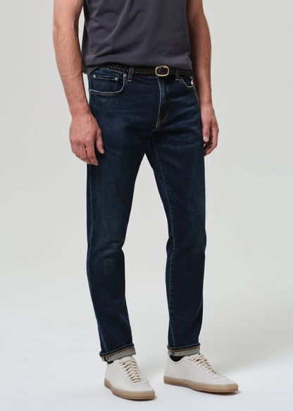 Person wearing grey tee with dark indigo jeans