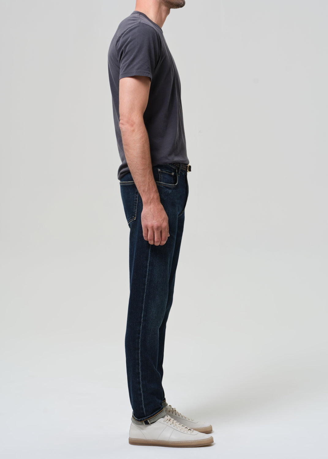Person wearing grey tee with dark indigo jeans