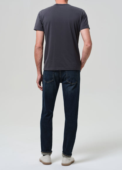 Person wearing grey tee with dark indigo jeans