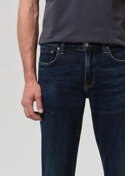 Person wearing grey tee with dark indigo jeans